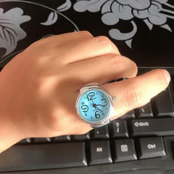 Anillo reloj plateado con forma de flor y números grandes, elegante y único, ideal para estudiantes.